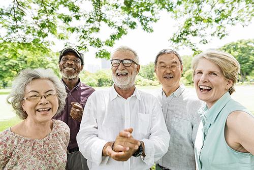 A group of older people laughing in a park.